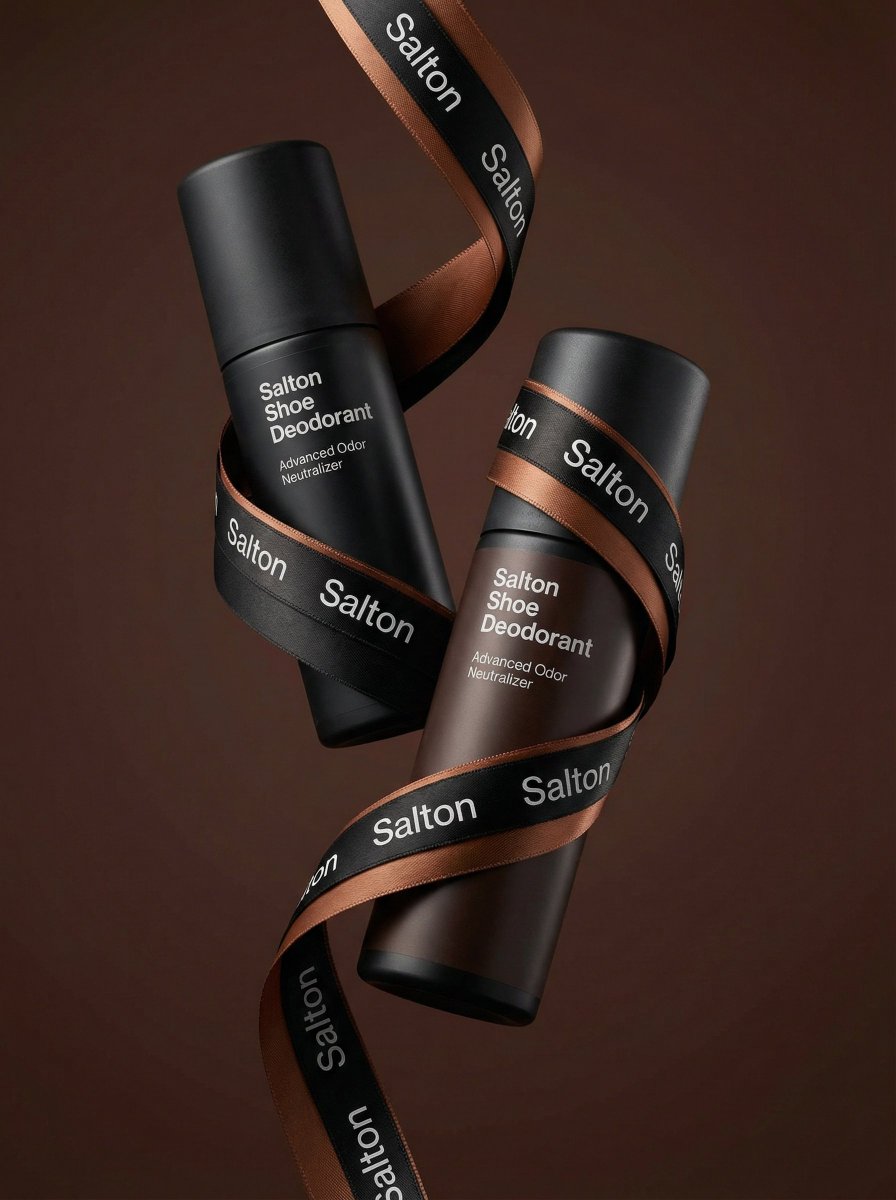 Two matte black deodorant bottles wrapped with a black and copper ribbon on a brown background.